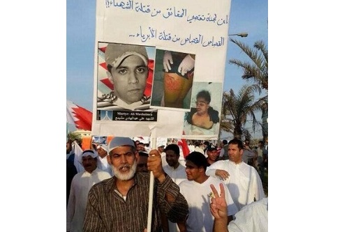 عبدالهادي مشيمع يحمل صورة ابنه الذي قتلته قوات الأمن